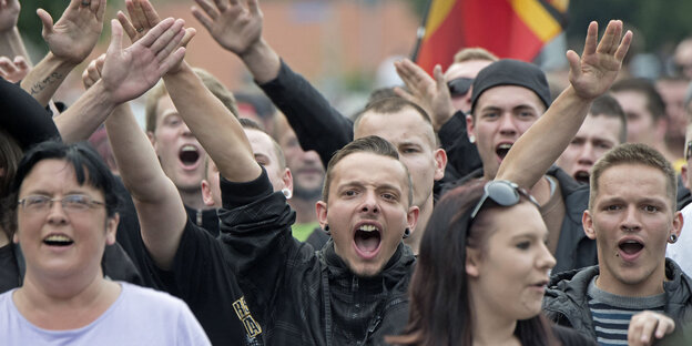 Eine größere Gruppe von Menschen. Sie demonstrieren und strecken die Arme hoch. Eine größere Gruppe von Menschen. Sie demonstrieren und strecken die Arme hoch.