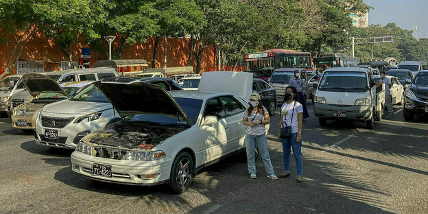 Demonstrantinnen stehen neben ihren Autos, die Motorhauben einiger Wagen sind aufgeklappt