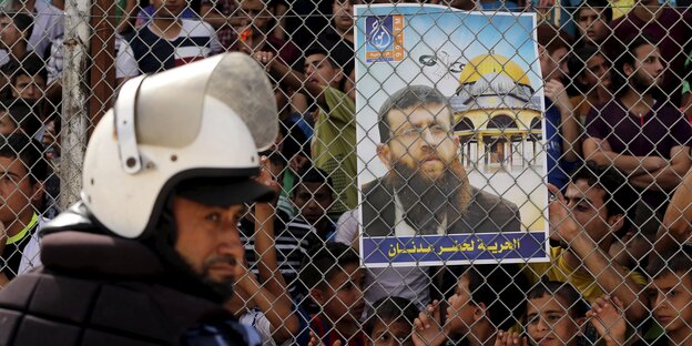 Ein Polizist läuft an einem Plakat mit dem Bild von Khader Adnan vorbei Ein Polizist läuft an einem Plakat mit dem Bild von Khader Adnan vorbei