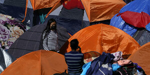 Dicht aneinander gedrängte Zelte sind zu sehen, dazwischen einige MigrantInnen