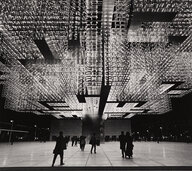 Schwarzweißfotografie von Timm Rautert in der die Menschen unter der mächtig mit Lampen verhangenen Decke des Schweizer Pavillons klein schrumpfen