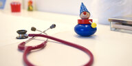 Ein Stethoskop und eine Spielzeugfigur liegen auf einem Tisch