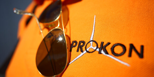 Prokon-T-Shirt auf dem eine Sonnenbrille liegt Prokon-T-Shirt auf dem eine Sonnenbrille liegt