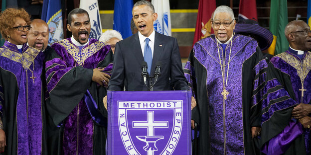 Barack Obama am Rednerpult in einer Kirche, hinter ihm Geistliche Barack Obama am Rednerpult in einer Kirche, hinter ihm Geistliche