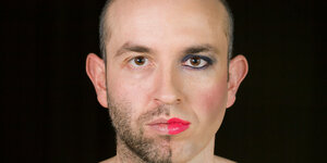 Portrait einen Mannes, der eine Gesichtshälfte weiblich geschminkt hat