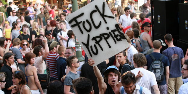 Demonstrant hält Plakat mit Inschrift "Fuck Yuppies" hoch Demonstrant hält Plakat mit Inschrift "Fuck Yuppies" hoch