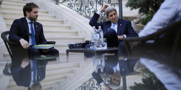 John Kerry sitzt mit zwei weiteren Männern an einem Tisch John Kerry sitzt mit zwei weiteren Männern an einem Tisch