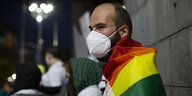 Mann im Profil trägt Regenbogenfahne und Maske