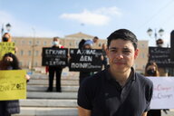 Seán Binder ist in Athen vor Demonstrierenden zu sehen, die zu Solidarität mit den angeklagten Aktivist:innen aufrufen.