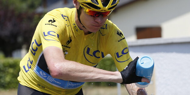 Tour de France-Fahrer Christ Froome im gelben Trikot. Er sitzt auf einem Fahrrad und spritzt sich mit einer Flasche Wasser ab. Tour de France-Fahrer Christ Froome im gelben Trikot. Er sitzt auf einem Fahrrad und spritzt sich mit einer Flasche Wasser ab.