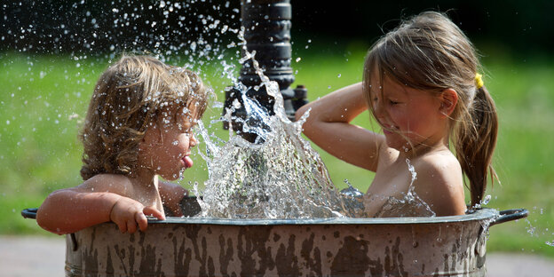 Zwei Kinder sitzen in einem Bottich voll Wasser Zwei Kinder sitzen in einem Bottich voll Wasser