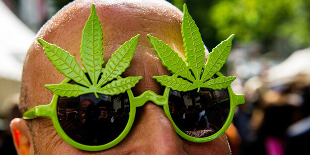 Ein Mann trägt eine Brille in Cannabisblatt-Form Ein Mann trägt eine Brille in Cannabisblatt-Form