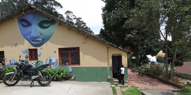 Ein Wandgemälde mit einem freundlich schauenden blauen Gesicht ziert die gelbe Wand des Verwaltungsgebäudes der Kinderrepublik Benposta oberhalb von Kolumbiens Hauptstadt Bogotá Ein Wandgemälde mit einem freundlich schauenden blauen Gesicht ziert die gelbe Wand des Verwaltungsgebäudes der Kinderrepublik Benposta oberhalb von Kolumbiens Hauptstadt Bogotá