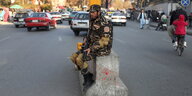 Ein bewaffneter Taliban sitzt an einem Checkpoint in Kabul
