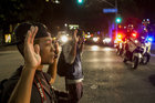 Zwei Männer knien mit erhobenen Händen auf der Straße, dahinter Polizei-Blaulicht