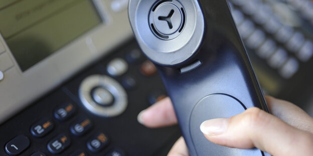 Eine Frau hält einen Telefonhörer in der Hand. Eine Frau hält einen Telefonhörer in der Hand.