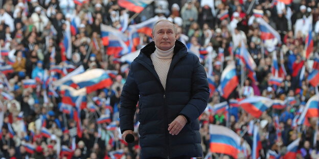 Vladimir Putin vor Publikum mit russischen Flaggen