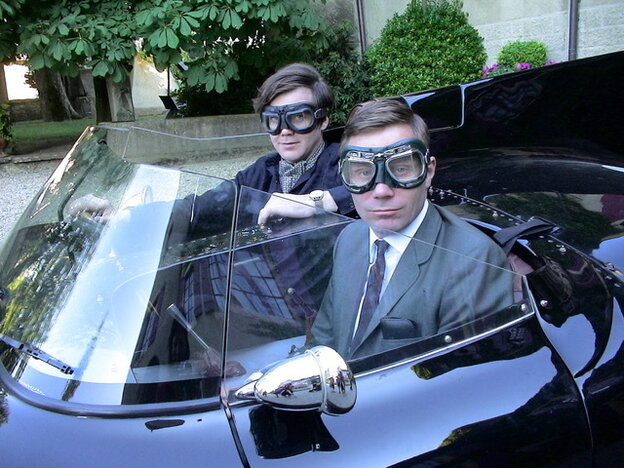 Toby Dammit und Thomas Wydler sitzen mit Fahrerbrillen in einem alten Cabriolet.