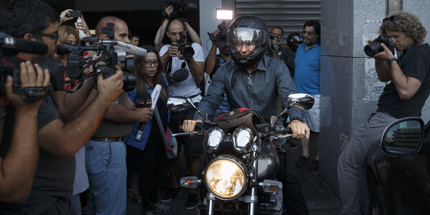 Gianis Varoufakis fährt Motorrad und ist von Journalisten umringt Gianis Varoufakis fährt Motorrad und ist von Journalisten umringt