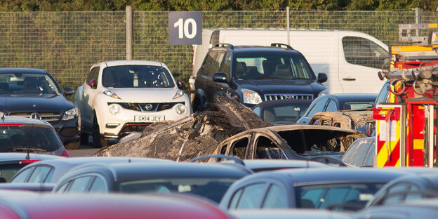 Zwischen parkenden Autos ist das Wrack der Maschine zu sehen