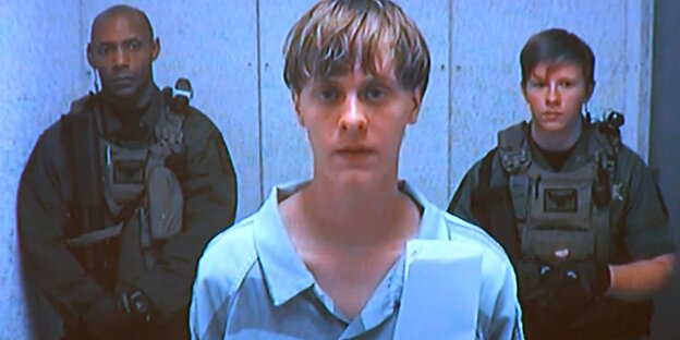 Dylann Roof in Sträflingsuniform, im Hintergrund zwei Wachmänner