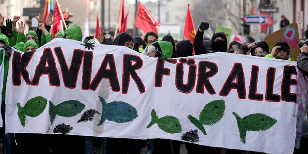 Demonstranten mit einem Banner, auf dem „Kaviar für alle“ steht