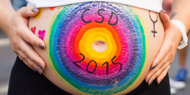 Mit Regenbogenfarben bemalter Bauch einer Schwangeren Mit Regenbogenfarben bemalter Bauch einer Schwangeren