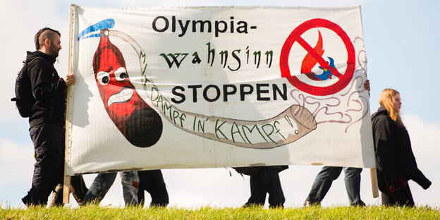 Olympia-Gegner mit Plakat auf einem Deich Olympia-Gegner mit Plakat auf einem Deich