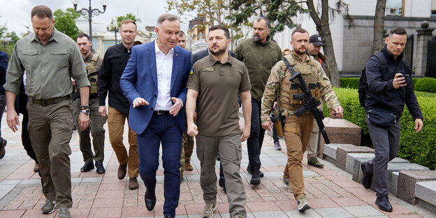 Präsident Duda und Präsident Selenskyi mit bewaffneten Personen.