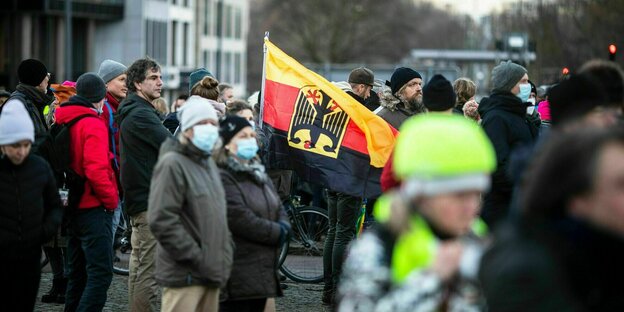 Eine Gruppe Menschen versammelt sich um eine umgedrehte Deutschlandfahne