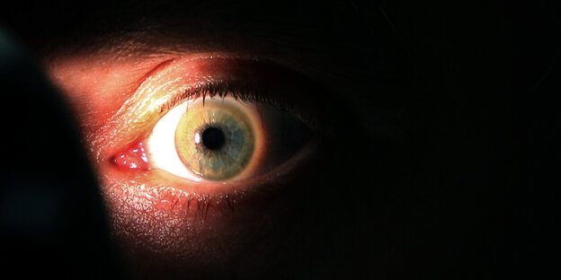 ein angeleuchtetes Auge im Dunkeln ein angeleuchtetes Auge im Dunkeln
