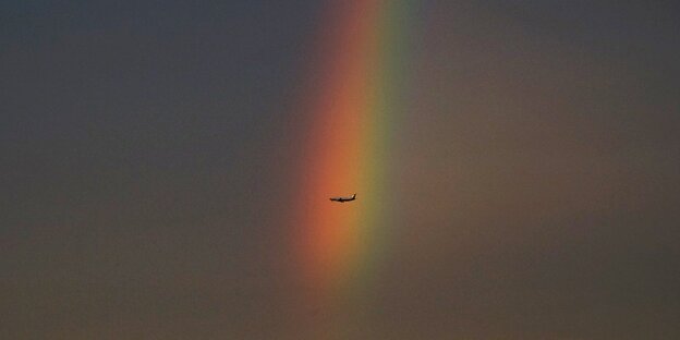 Ein Flugzeug fliegt durch einen Regenbogen Ein Flugzeug fliegt durch einen Regenbogen