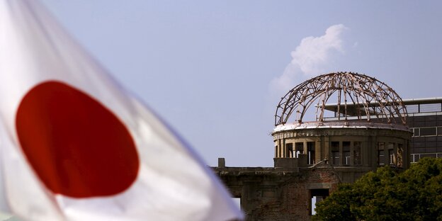 links im Vordergrund japanische Flagge, rechts dahinter Ruine in Hiroshima links im Vordergrund japanische Flagge, rechts dahinter Ruine in Hiroshima