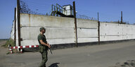 Ein Soldat patrouilliert auf der Straße vor der Mauer eines Gefängnisses