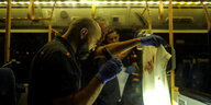 Im Innern eines Busses hält ein Uniformierter ein blutbeflecktes Tuch hoch