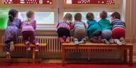 Kinder knien auf einer Bank und schauen aus dem Fenster