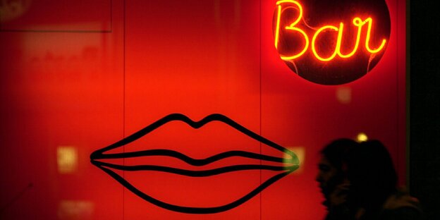 Passanten gehen in Frankfurt/Main an einer Erotik-Bar vorbei, die im rot beleuchteten Schaufenster mit übergroßen Lippen wirbt. Passanten gehen in Frankfurt/Main an einer Erotik-Bar vorbei, die im rot beleuchteten Schaufenster mit übergroßen Lippen wirbt.