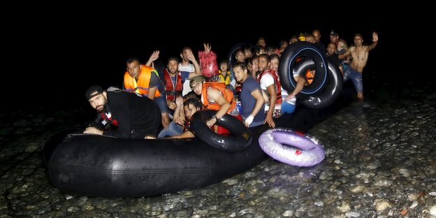 Männer in einem überfüllten Schlauchboot am Strand Männer in einem überfüllten Schlauchboot am Strand