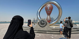 Eine Frau mir Nikab fotografiert eine Uhr, die die Zeit bis zum Beginn der Fussballweltnmeisterschaft angibt.
