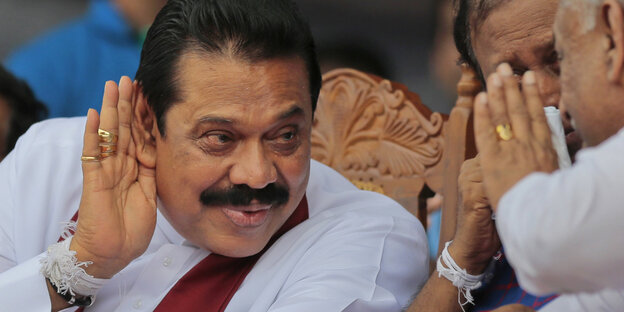 Mahinda Rajapaksa hält sich eine Hand hinter das Ohr Mahinda Rajapaksa hält sich eine Hand hinter das Ohr