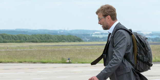 Jürgen Klopp, mit Rucksack, geht auf dem Rollfeld in Dortmund zum Flugzeug. Jürgen Klopp, mit Rucksack, geht auf dem Rollfeld in Dortmund zum Flugzeug.