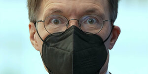 BundesGesundheitsminister Lauterbach mit fragendem Blick, er trägt eine schwarze Maske