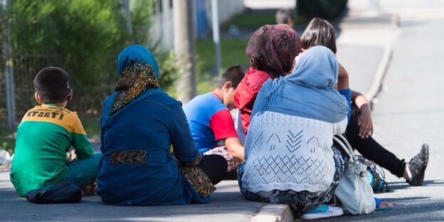 Flüchtlinge sitzen auf dem Bürgersteig Flüchtlinge sitzen auf dem Bürgersteig