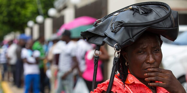 Haitianerin mit Tasche auf dem Kopf Haitianerin mit Tasche auf dem Kopf