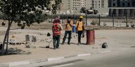 Drei Bauarbeiter mit Signaljacken arbieten in der Hitze an einer Straße