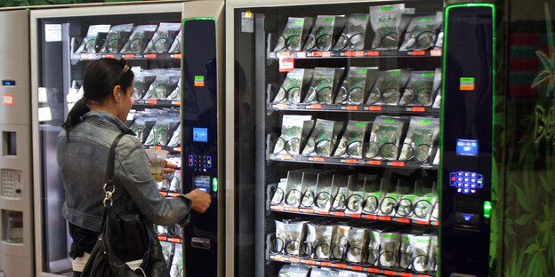 Frau vor einem Cannabis-Automaten Frau vor einem Cannabis-Automaten