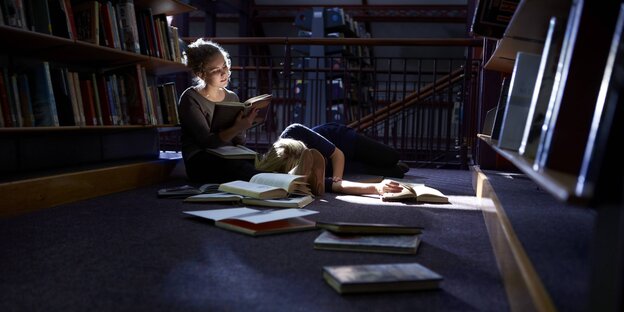 Studentinnen lernen in der Bibliothek. Eine ließt, die andere schläft. Studentinnen lernen in der Bibliothek. Eine ließt, die andere schläft.