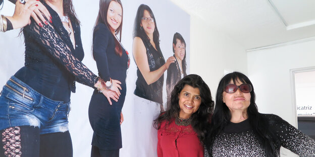 Zwei von Säureattentaten gezeichnete Frauen vor einem Plakat, das Säureopfer zeigt. Zwei von Säureattentaten gezeichnete Frauen vor einem Plakat, das Säureopfer zeigt.