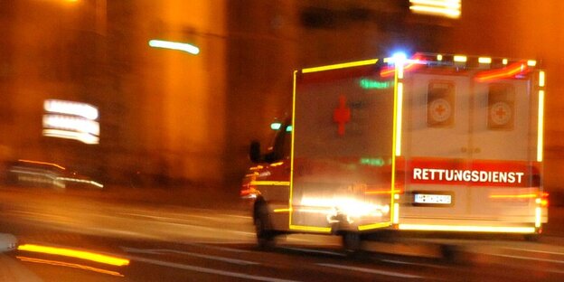 Ein Rettungswagen fährt durch eine beleuchte Straße. Ein Rettungswagen fährt durch eine beleuchte Straße.
