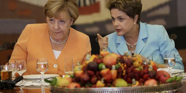 Angela Merkel und Dilma Rousseff sitzen hinter einem großen Haufen Obst Angela Merkel und Dilma Rousseff sitzen hinter einem großen Haufen Obst